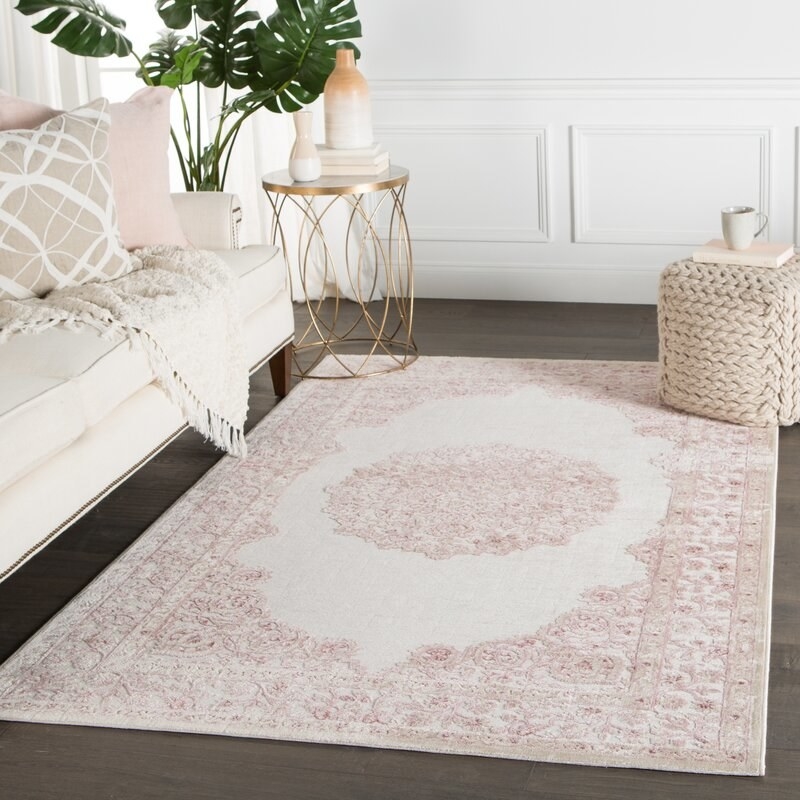 An area rug staged in a living room with soft vintage floral detailing 