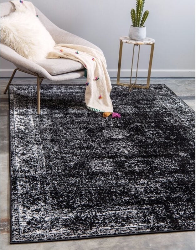 A large black rug with white and gray distressed detailing