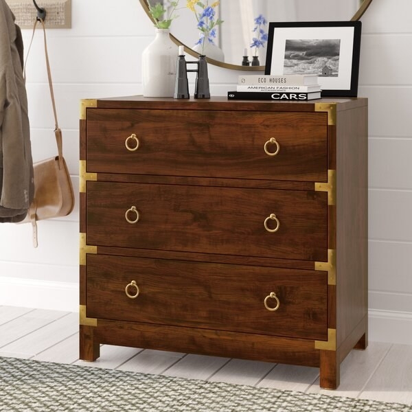 dark wood tone storage chest with three drawers and brass-tone ring-style drawer pools and accent hardware