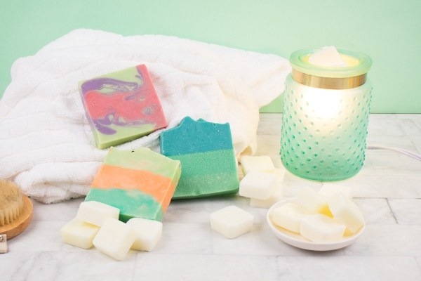 Three colorful soaps and several wax melts scattered next to an aqua-colored wax warmer