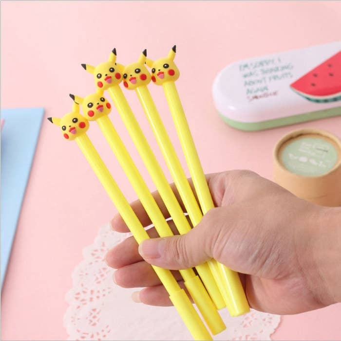 a hand holds a bunch of yellow pens topped with pikachu heads