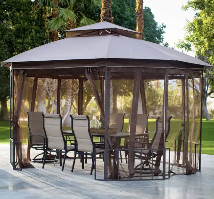 a gazebo top shaped like an octagon with loose, flowing netted curtains hanging down the sides around a set of outdoor furniture