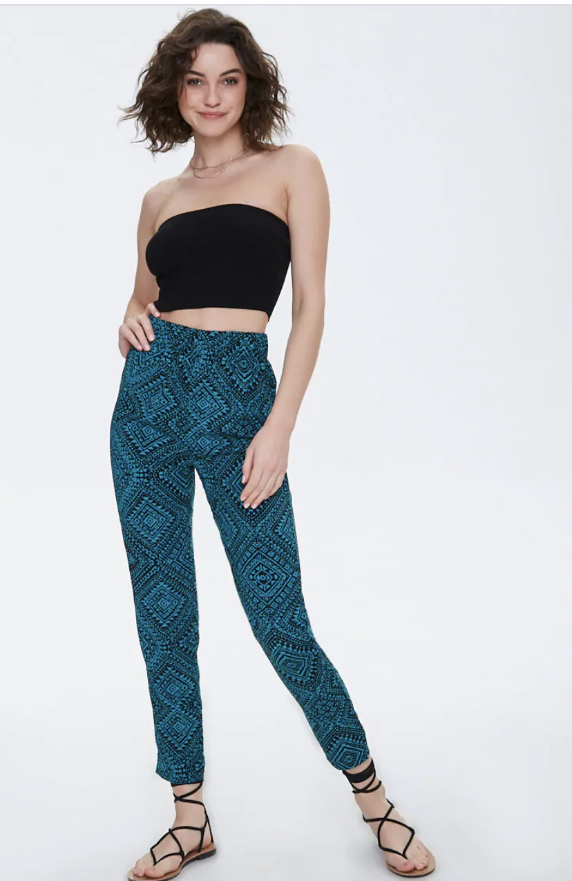 A person wearing high-rise geoprint pants with a crop top and sandals 