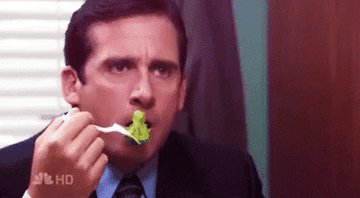 Michael Scott from the office eating a piece of broccoli.