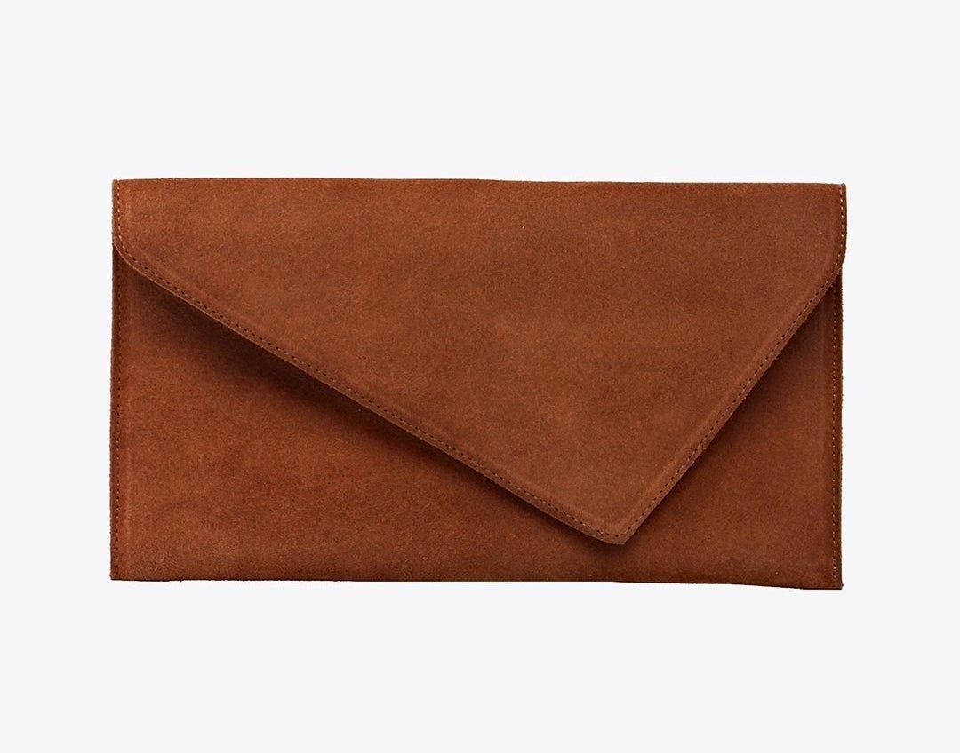 A brown suede clutch with a pointed flap that points to the right