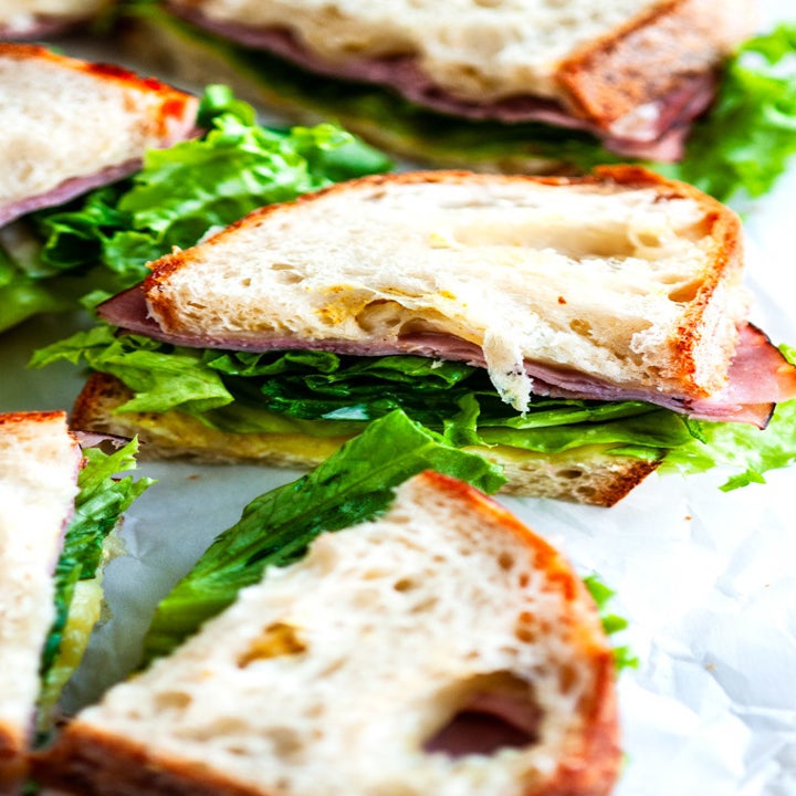 Multiple sandwich halves, stuffed with deli meat, cheese, lettuce, and condiments.