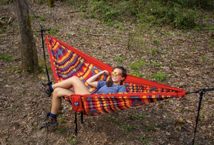 person sitting in a red patterned hammock 
