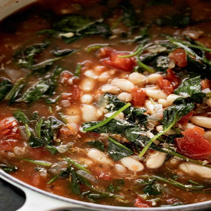 A big pot of white bean soup with diced tomatoes and kale.