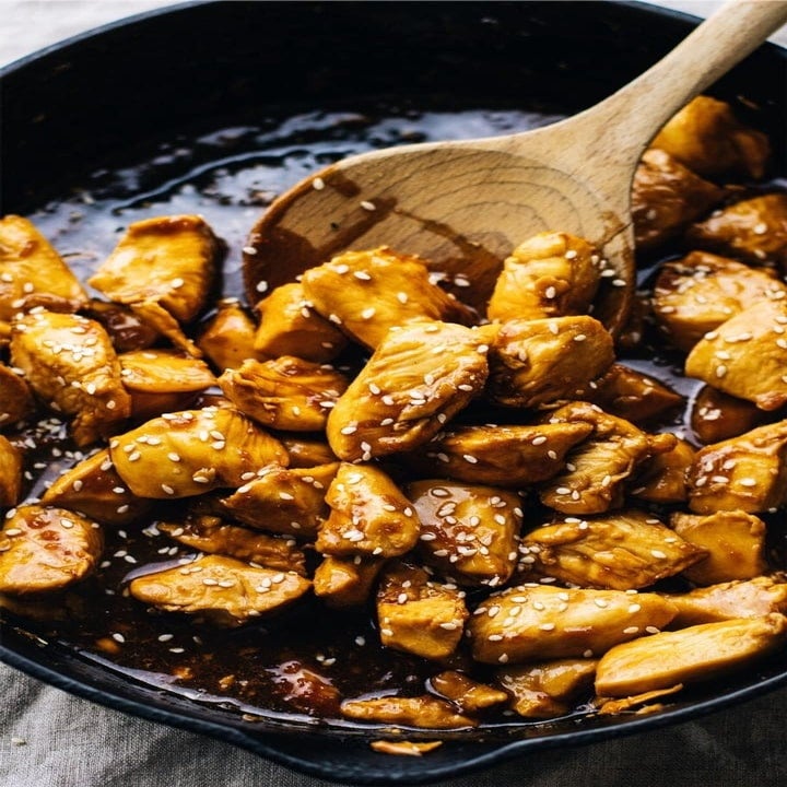 Sticky teriyaki chicken cooking in a skillet.