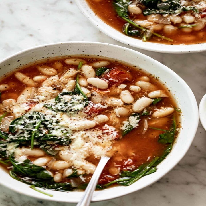 A bowl of the finished white bean soup with grated Parmesan cheese.