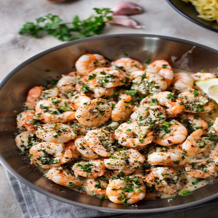 A skillet full of shrimp scampi tossed with parsley and herbs.