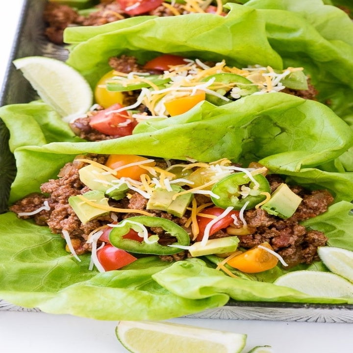 A platter of lettuce wraps filled with ground beef, cheese, avocado, jalapeño.
