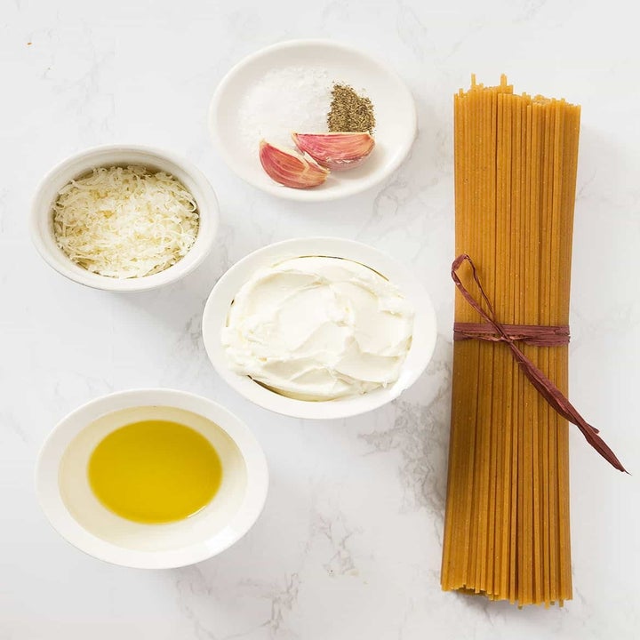 Ingredients for pasta including spaghetti, cream cheese, olive oil, and cheese.
