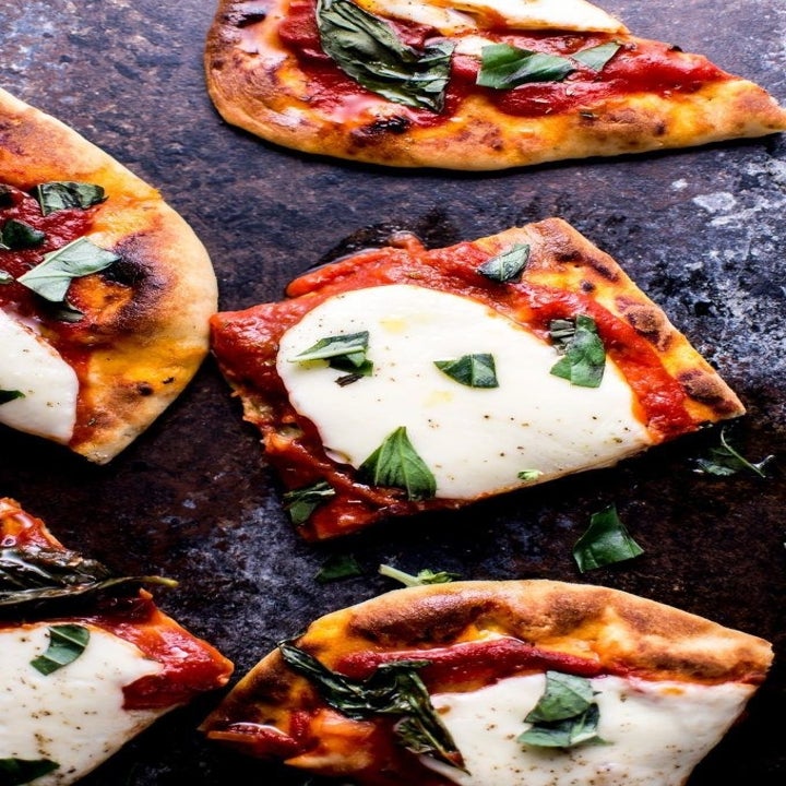 A cut up naan pizza topped with tomato sauce, mozzarella cheese, and basil.