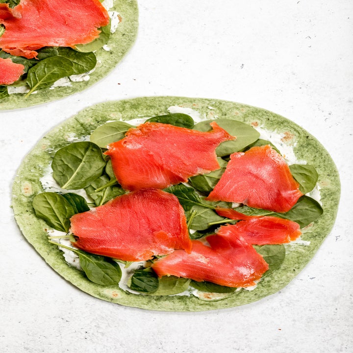 A spinach tortilla topped with cream cheese, spinach, and smoked salmon.