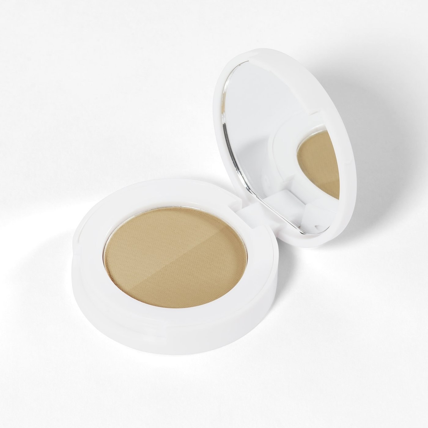 A small mirrored compact with a lighter shade of powder on one side and a darker shade on the other side