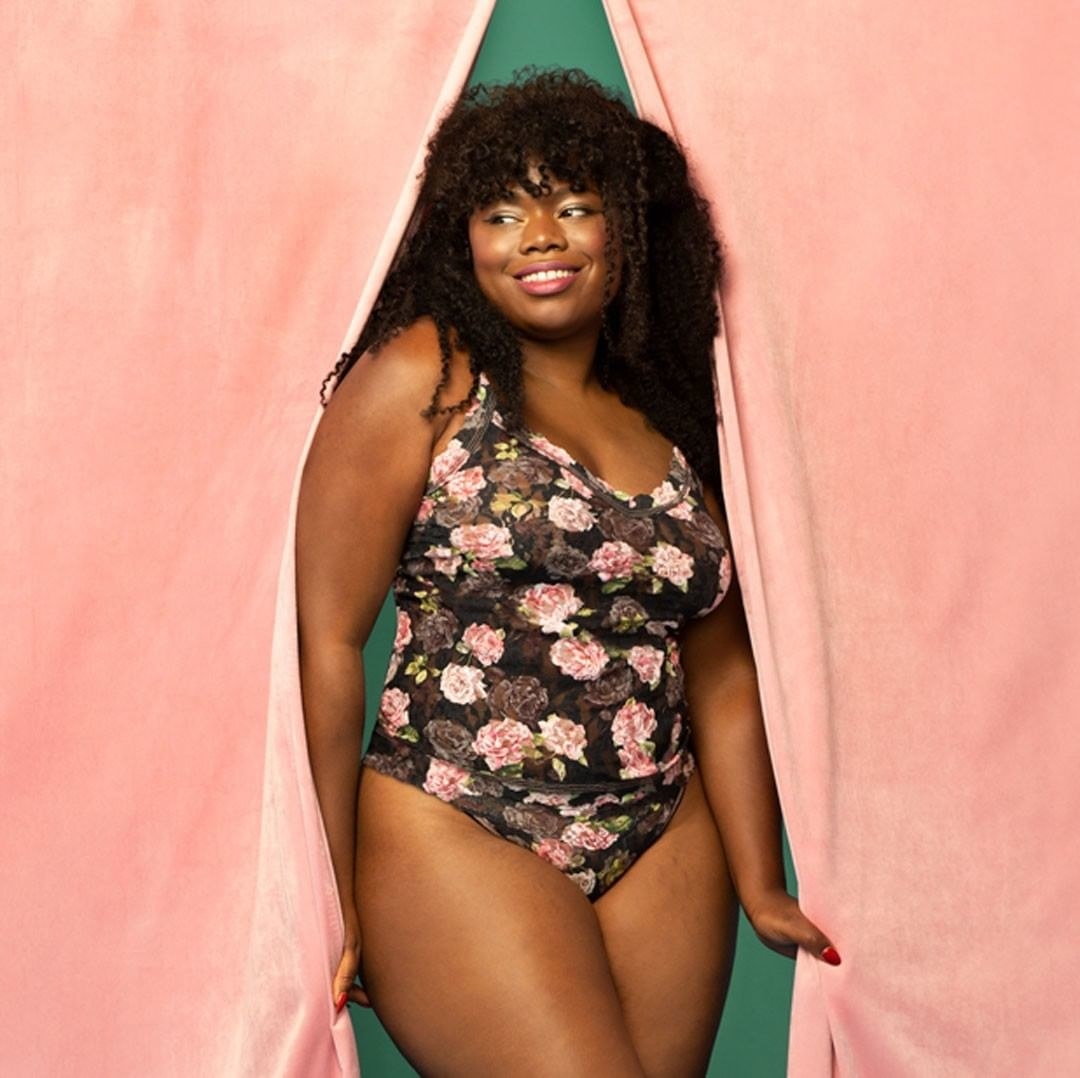 Model wearing Shadow Roses plus size classic cami and matching underwear posing with a pink curtain