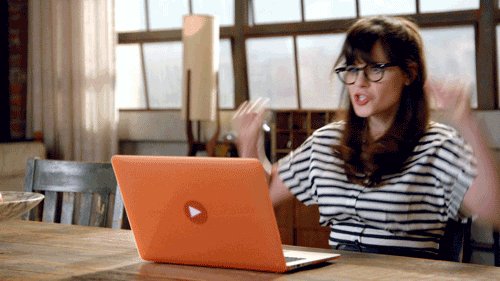 Jess from New Girl cheers in front of a laptop