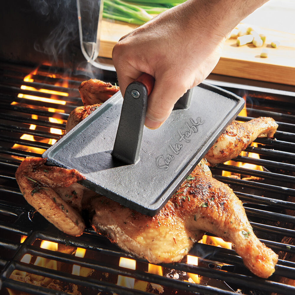 hand using product to press a chicken onto a grill