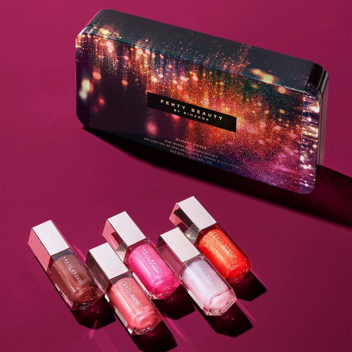 sparkly-looking packaging for the glosses next to the five glosses which are all shimmery and include shades of bergundy, three pinks, and orange