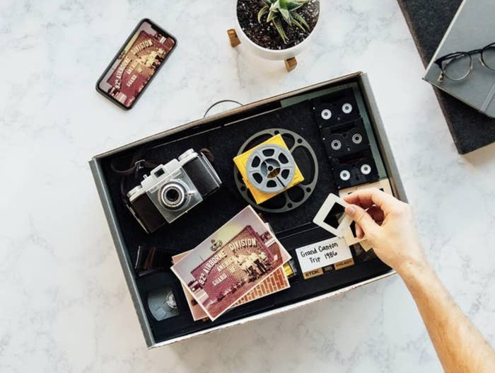 A box containing an old camera, film, postcards,