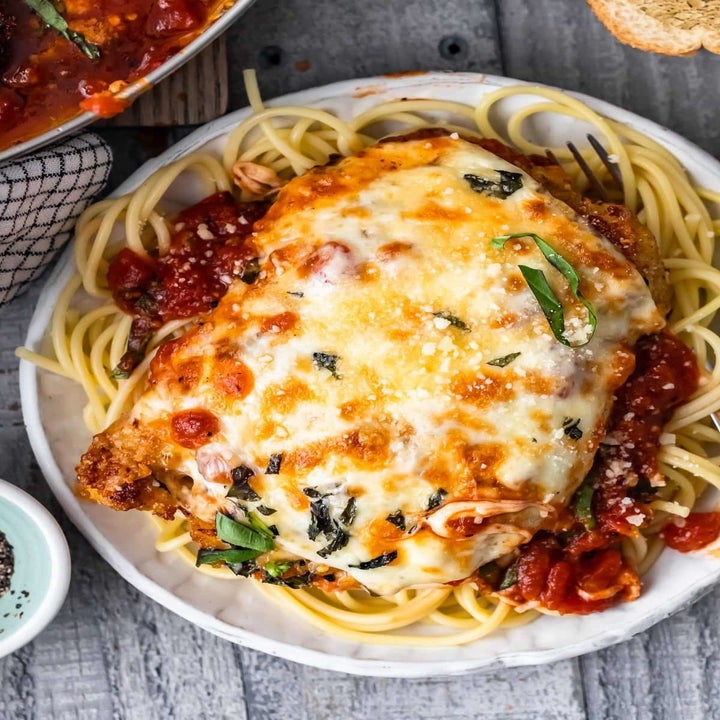 A plate of crispy, cheesy chicken parmesan on top of spaghetti.
