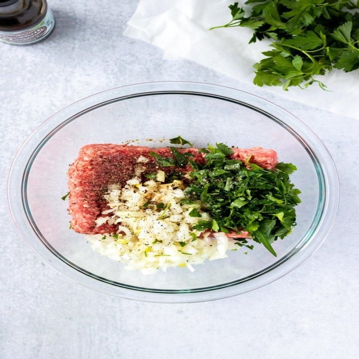 Ground beef, garlic, onion, and herbs in a bowl for making hamburger patties.