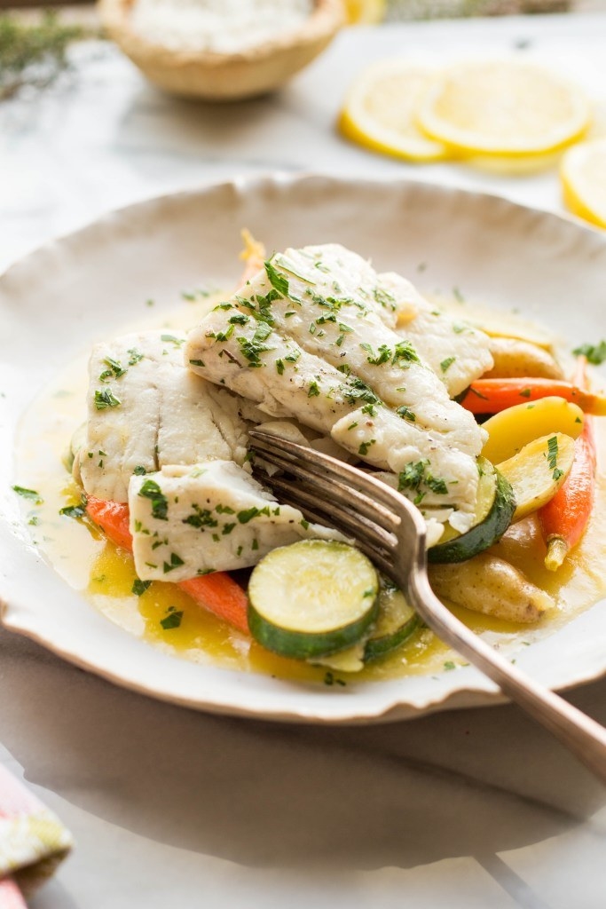 Poached fish with tender vegetables on a plate.