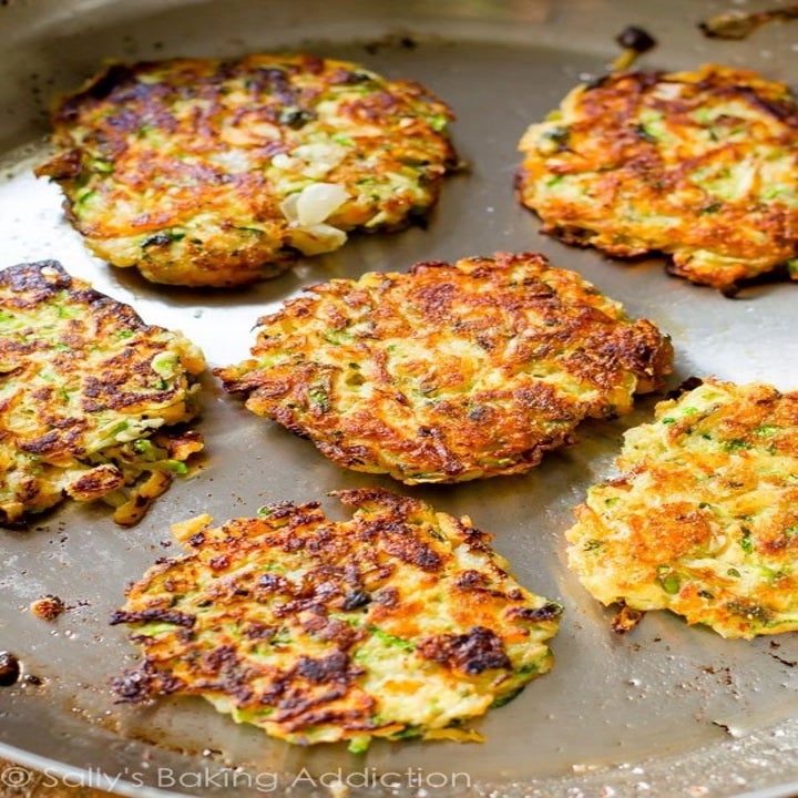 6 golden brown vegetable pancakes in a skillet.