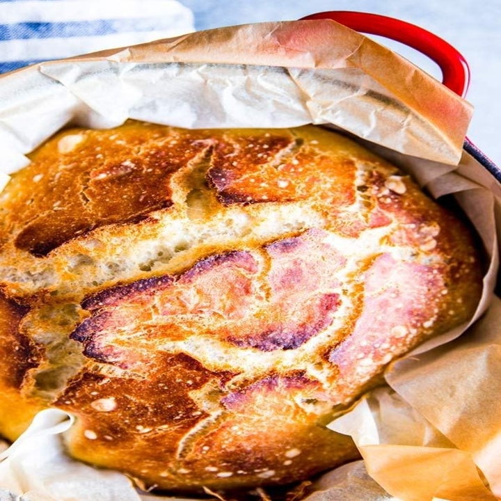 A crispy, golden loaf of freshly baked bread in a Dutch oven.