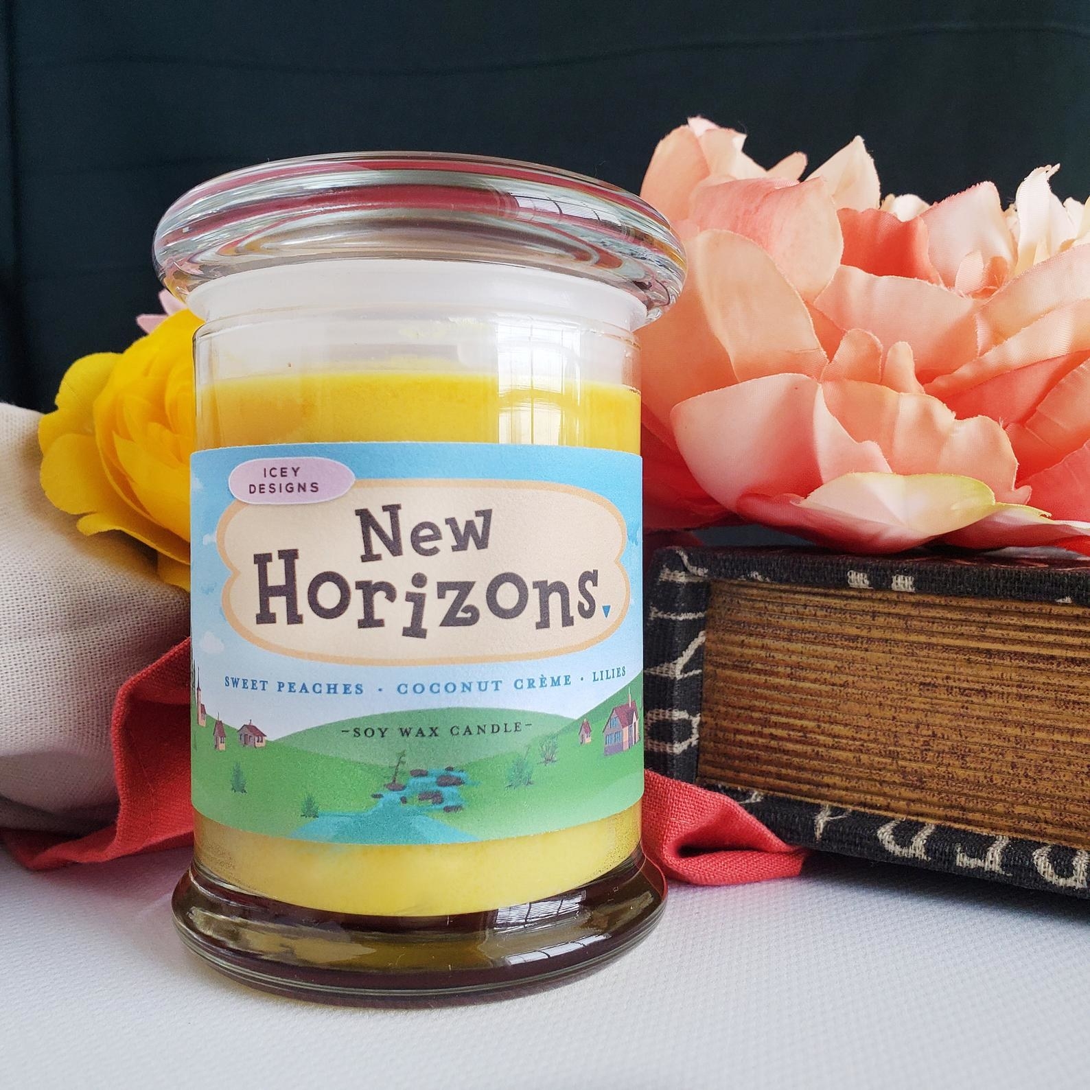 A glass candle with a glass lid with a sticker around it that says &quot;New Horizons&quot; 