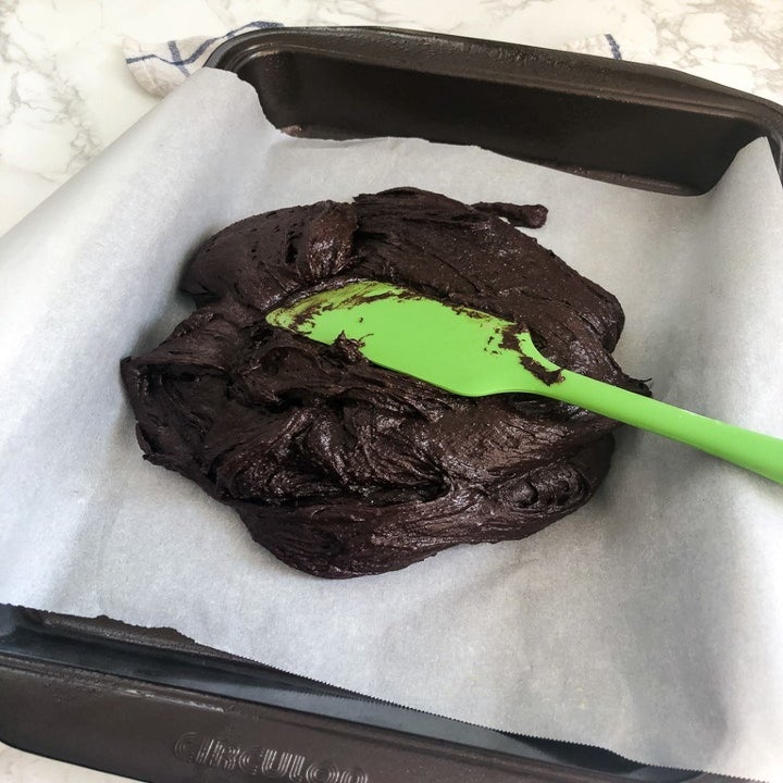 Fudgey brownie mixture on parchment paper on a sheet pan.