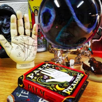 reviewer pic of book on a table with a crystal ball and palmistry hand