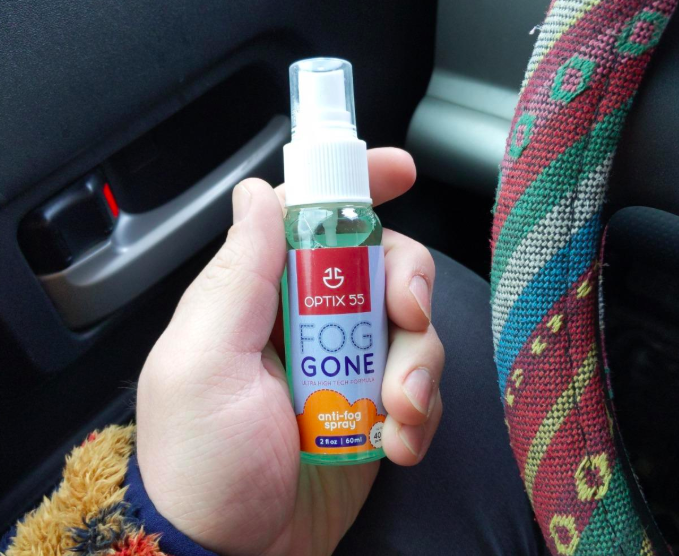 A customer review photo of them holding a bottle of Optix 55 Fog Gone spray