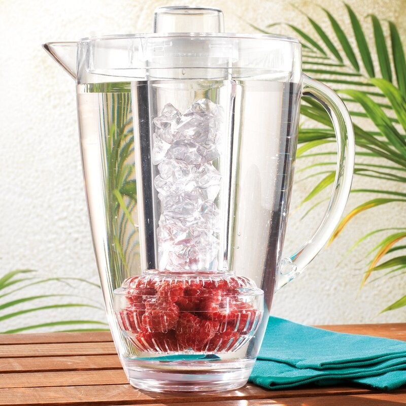 clear water pitcher with cover filled with berries and ice
