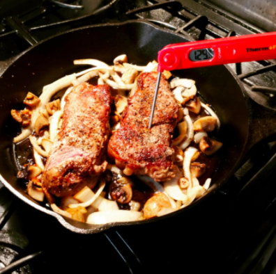 reviewer pic of meat thermometer stuck in steak on skillet on stove