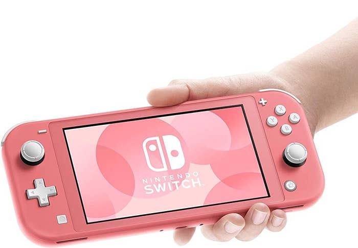 A hand holding pink Nintendo switch lite