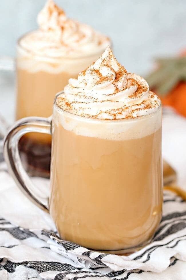 The latte inside a glass mug topped with whipped cream and cinnamon