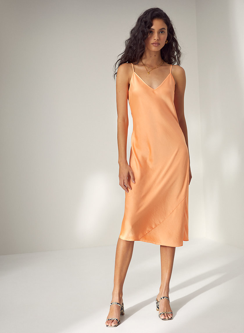 Model wearing the dress in a sherbet-y orange