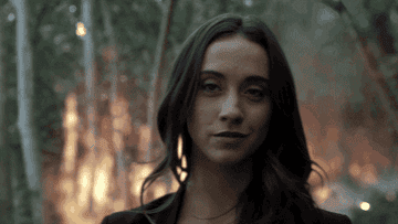 Julia Wicker from &quot;The Magicians&quot; smirks while walking away from a forest fire 