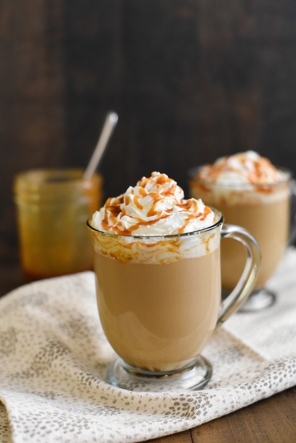 The latte inside a glass mug topped with whipped cream and a caramel drizzle