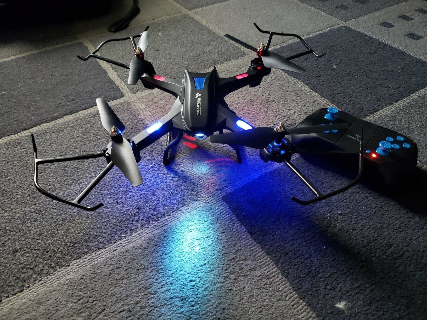 An idle drone with a controller lit up on a reviewer&#x27;s floor