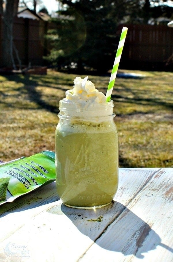 The green-colored blended drink in a glass mason jar topped with whipped cream
