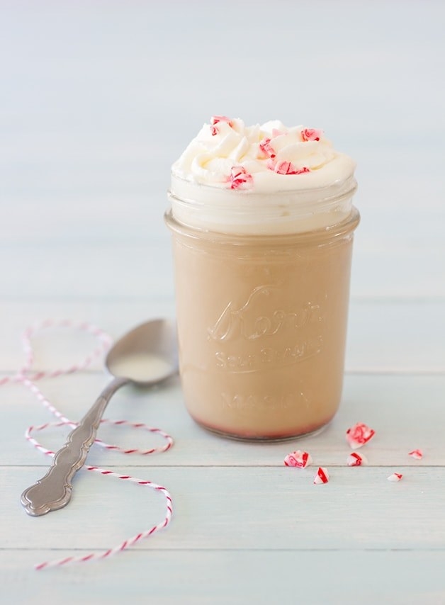 The white chocolate drink inside a glass Mason jar topped with whipped cream and peppermint candy pieces