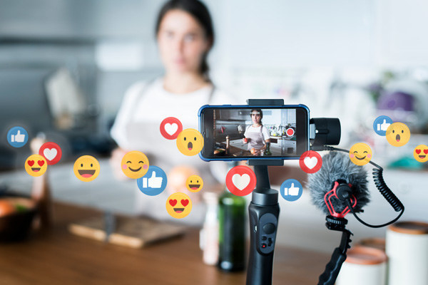 person shooting iphone video on a tripod with illustrated emoji reacts coming out of the screen