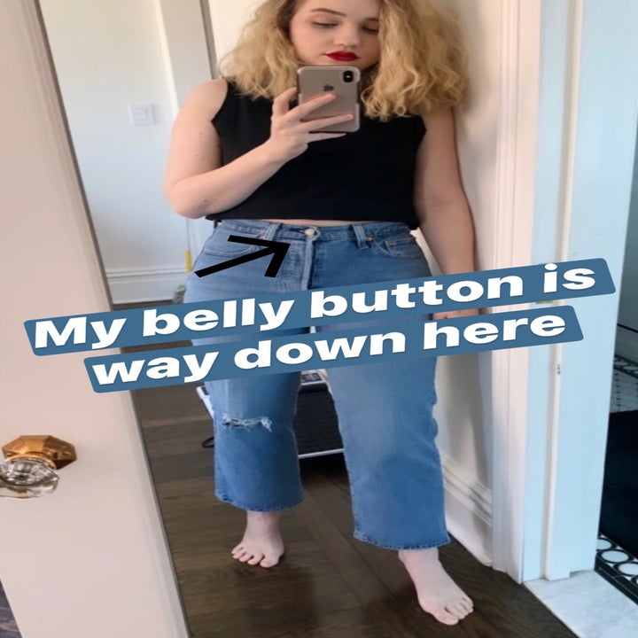 BuzzFeed Senior Editor Maitland Quitmeyer wearing blue jeans labeled "my belly button is way down here" to show the high waist
