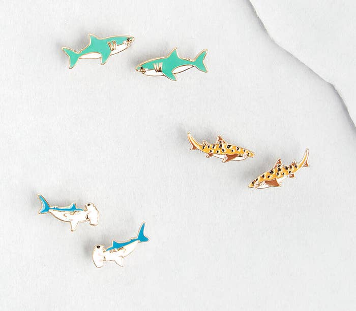 Three pairs of earrings shaped like great white sharks, hammerhead sharks, and leopard sharks