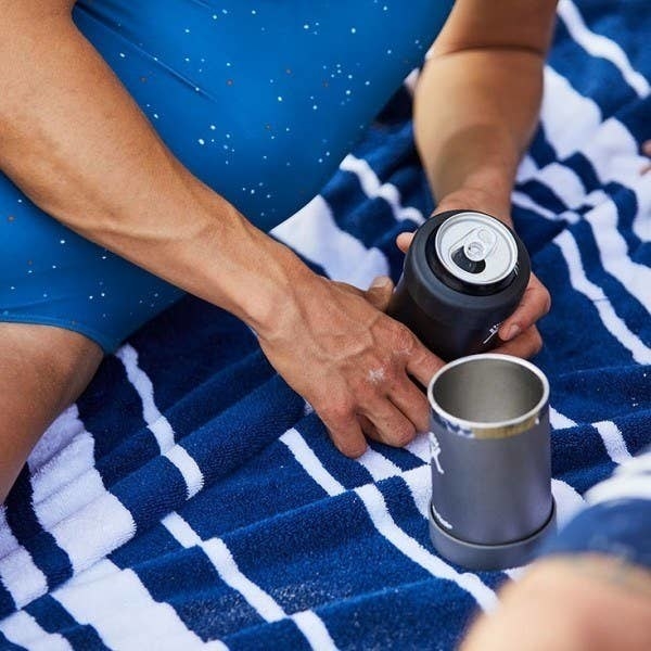 One grey cooler cup being used as a cup and another in a model&#x27;s hands with a can inside
