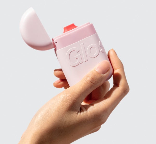 A model holding the hand cream, which has a pink container