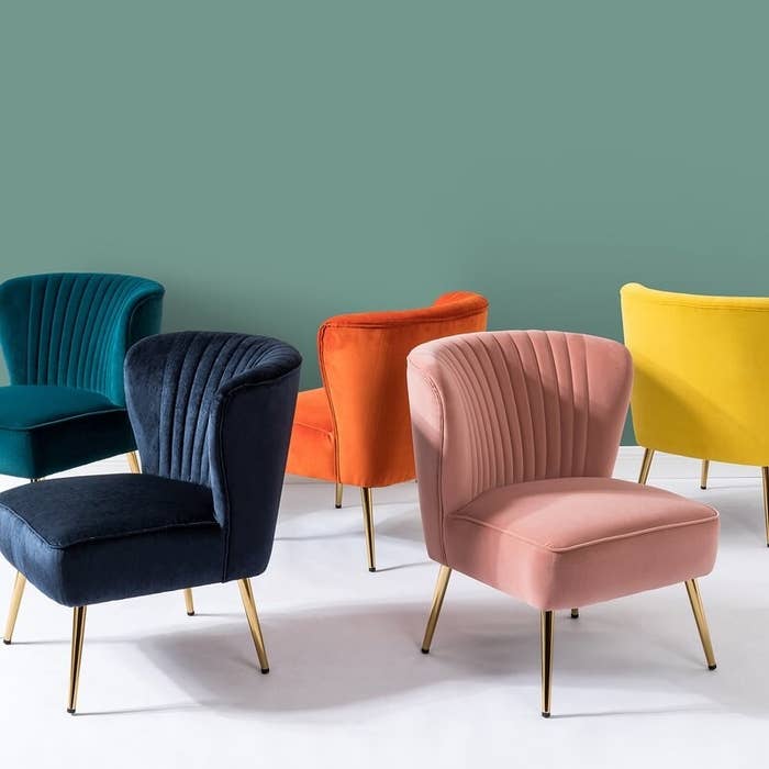 Multiple side chairs in different colors, each with a rounded, tufted back and tapered metal legs